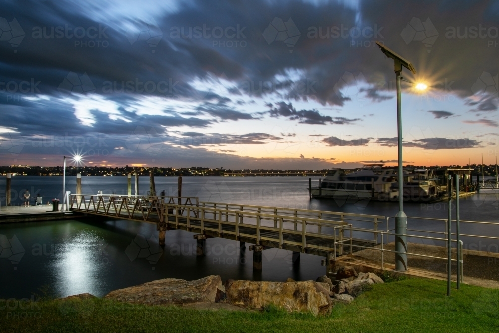 A small jetty with lights on it extends into Botany Bay at sunset - Australian Stock Image