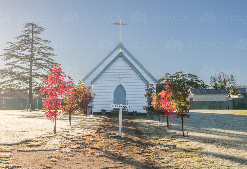 A small white church under a blue sky on an autumn morning - Australian Stock Image