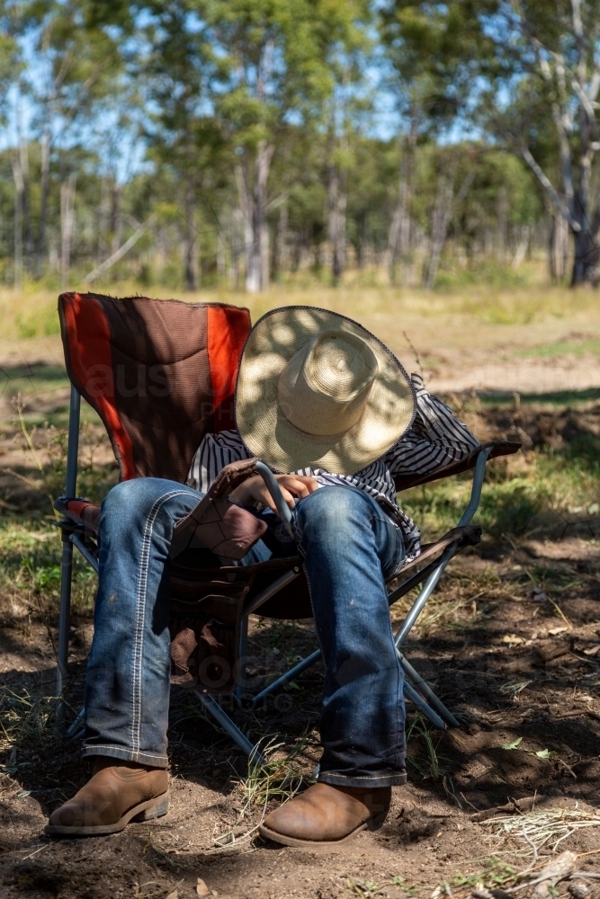 A teenage girl having a nap lounging in camp chair, with hat covering face. - Australian Stock Image