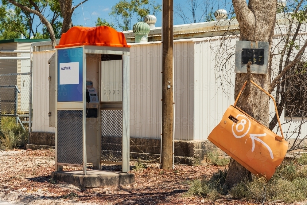 A telephone booth next a car door hanging on a tree in an outback community - Australian Stock Image