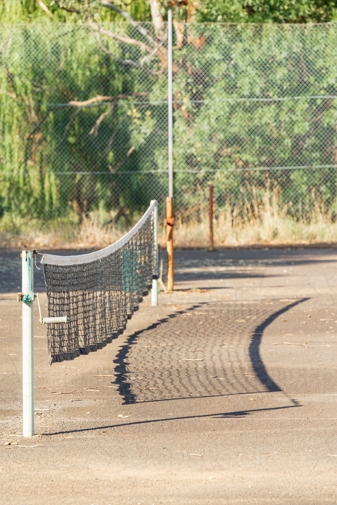 A tennis net and its shadow on an empty tennis court - Australian Stock Image