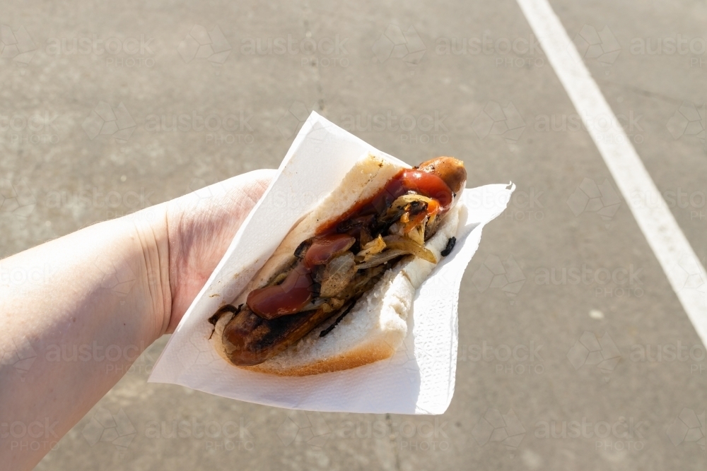 A traditional Australian barbequed sausage in bread with onions and tomato sauce - Australian Stock Image