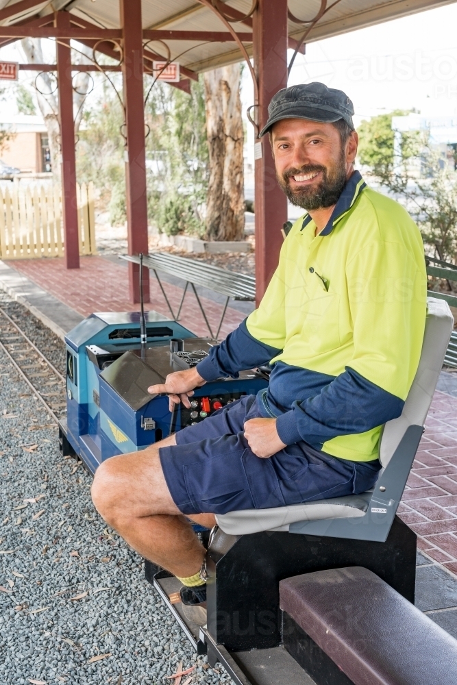 A train driver sitting aboard the controls of a miniature train - Australian Stock Image