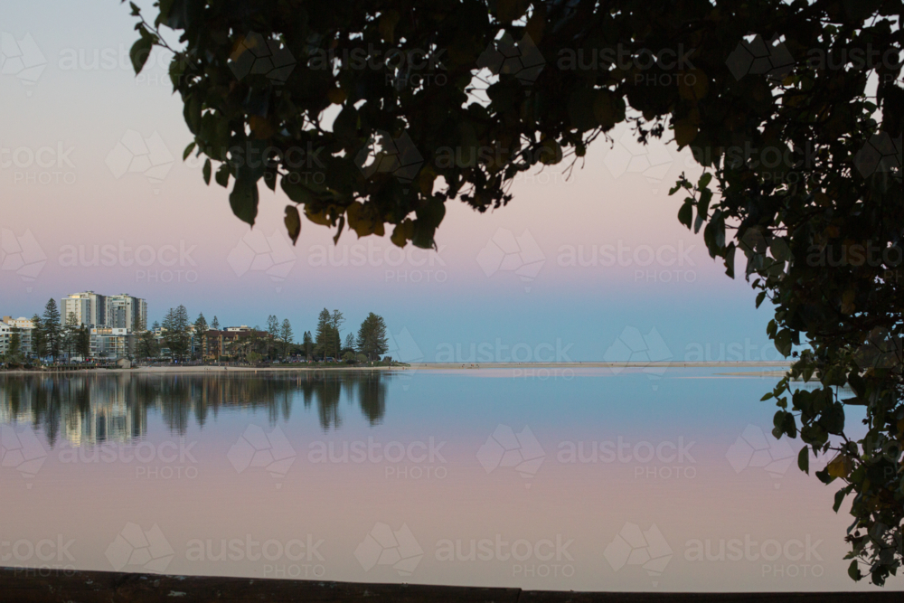 A tranquil waterfront cityscape at twilight, with pastel sky and a reflection of buildings - Australian Stock Image