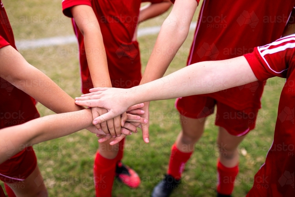 A tween girls football team joining hands in preparation for a match - Australian Stock Image