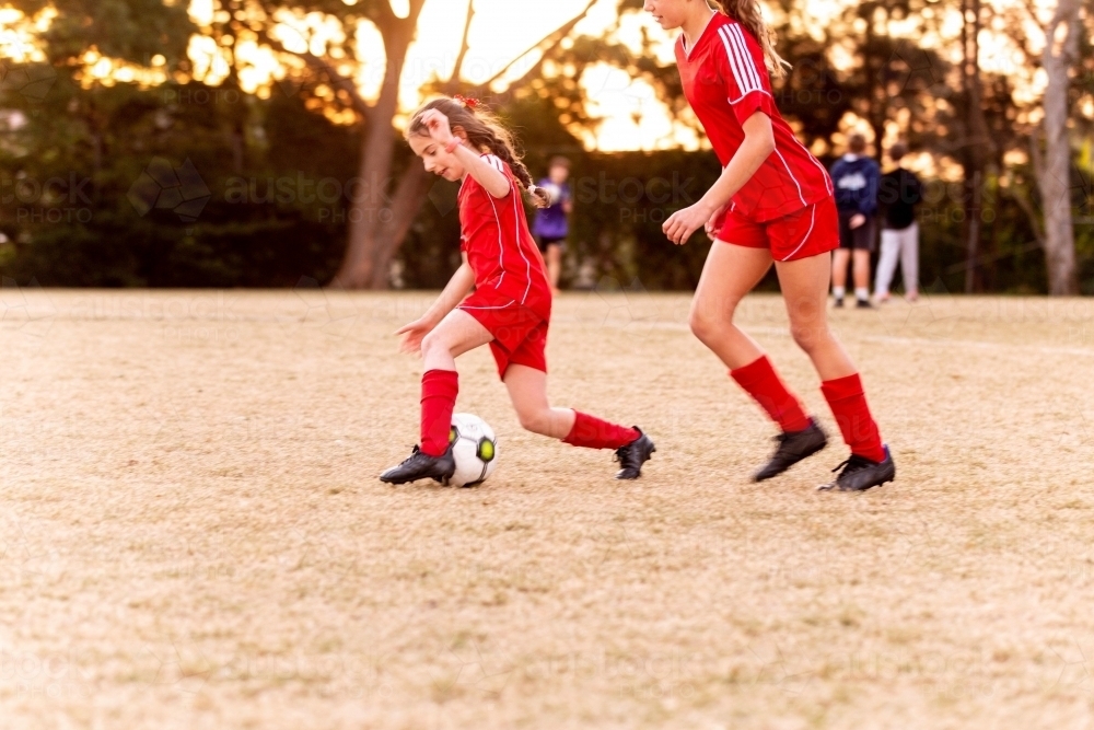 A tween girls football team training together at a sports oval - Australian Stock Image