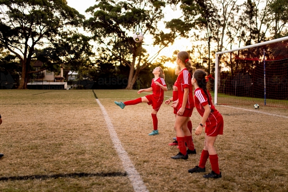 A tween girls football team training together at a sports oval - Australian Stock Image