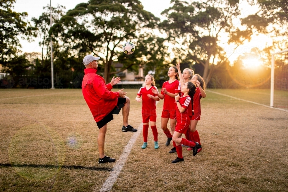 A tween girls football team training together at a sports oval - Australian Stock Image