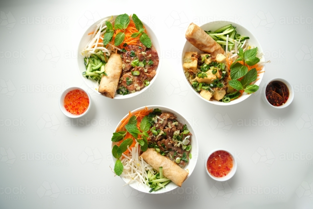 A variety of Bun Cha Gio bowls on a white countertop with a small dishes of chili sauce on the side. - Australian Stock Image