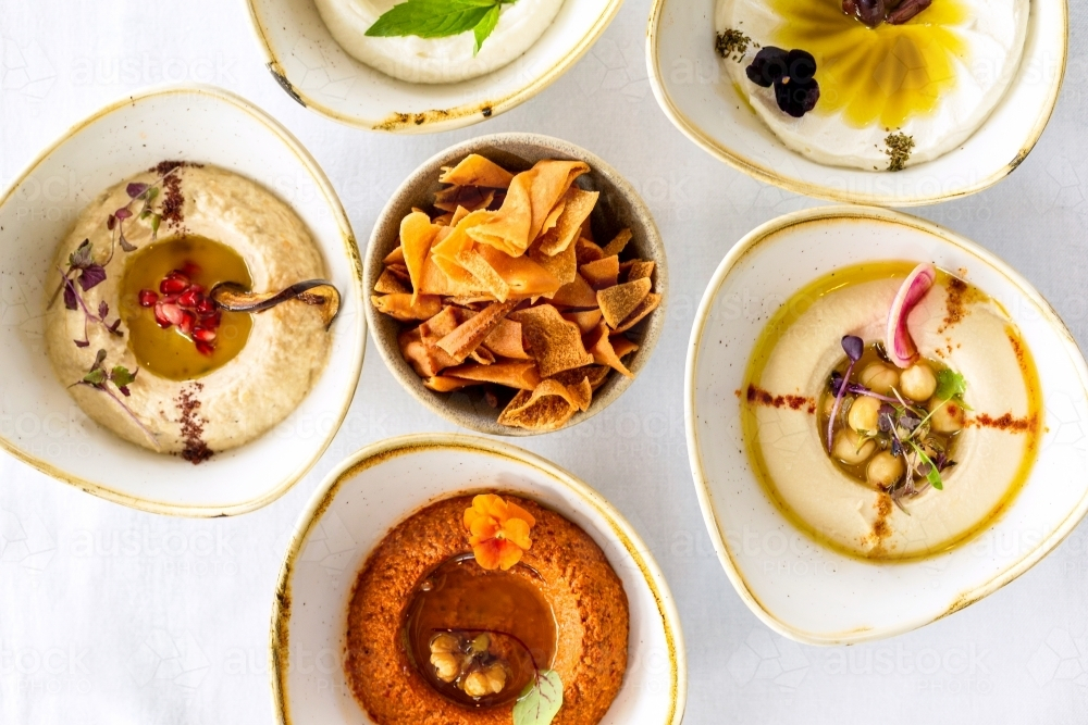 A variety of hummus dips arranged on a white countertop. - Australian Stock Image