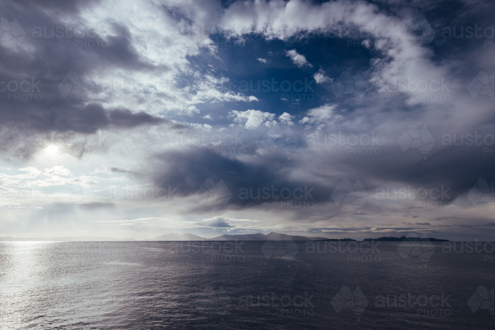 A view towards the morning rising sun over the Hazards of Freycinet Peninsula from Swansea, Tasmania - Australian Stock Image