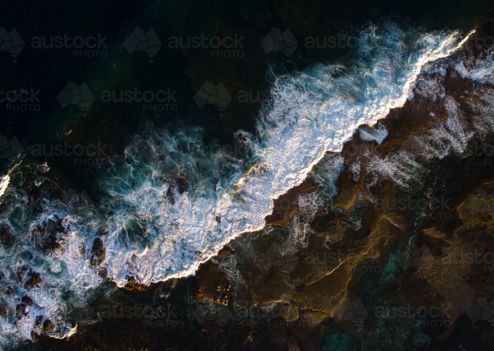 A wave breaks gently over an exposed reef - Australian Stock Image