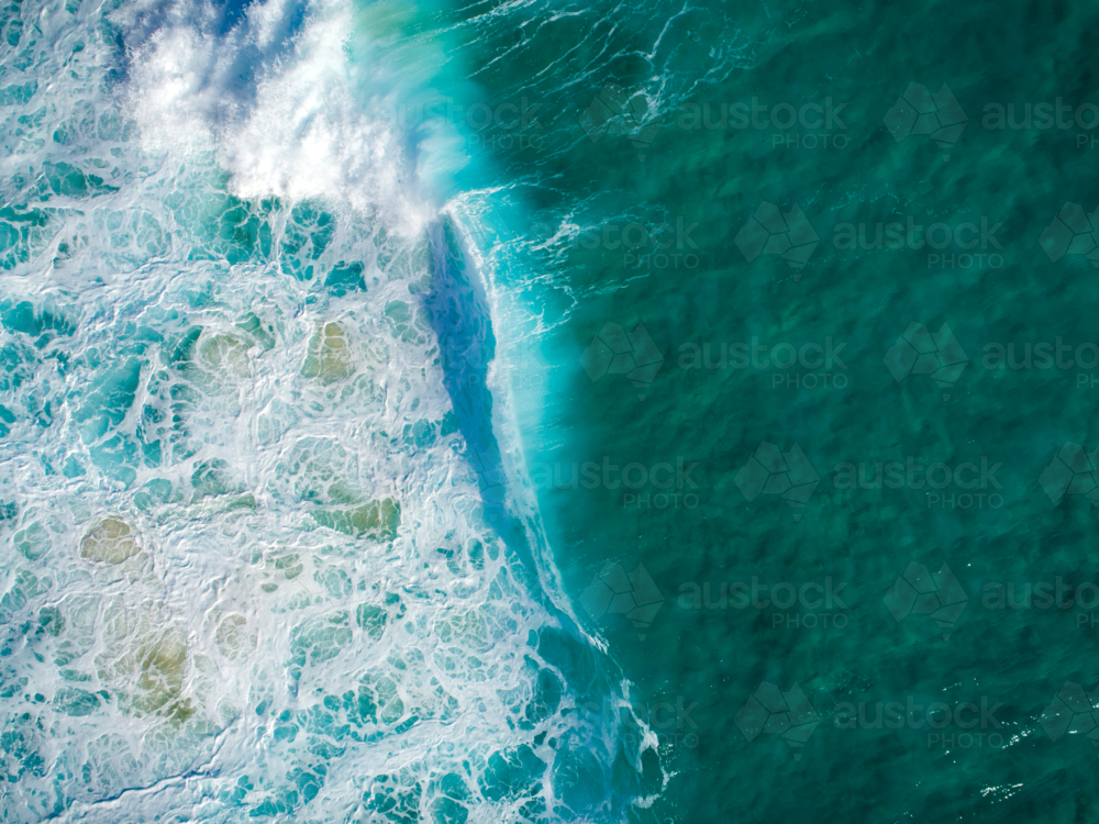 A wave breaks onto present white wash in the ocean - Australian Stock Image