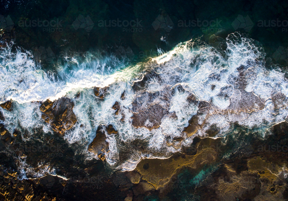 A wave crashed over an eposed reef after dawn - Australian Stock Image