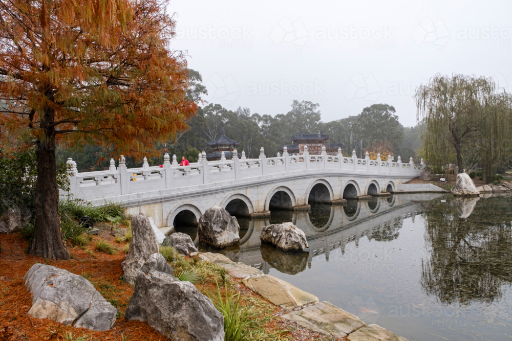 A white, multi-arched bridge crossing over a calm water. - Australian Stock Image