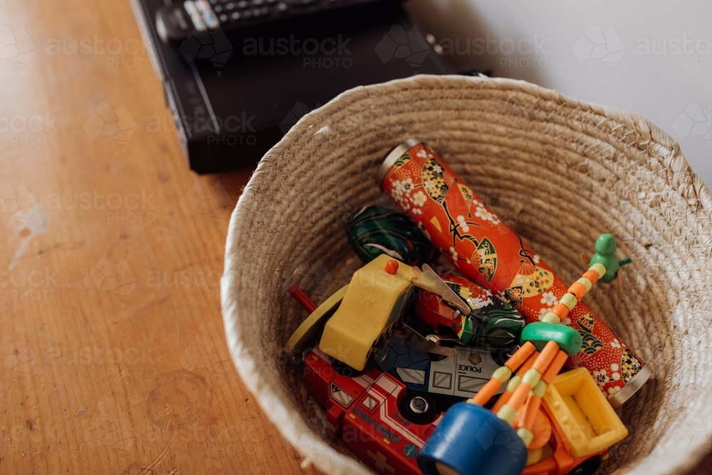 A woven basket filled with various small toys. - Australian Stock Image