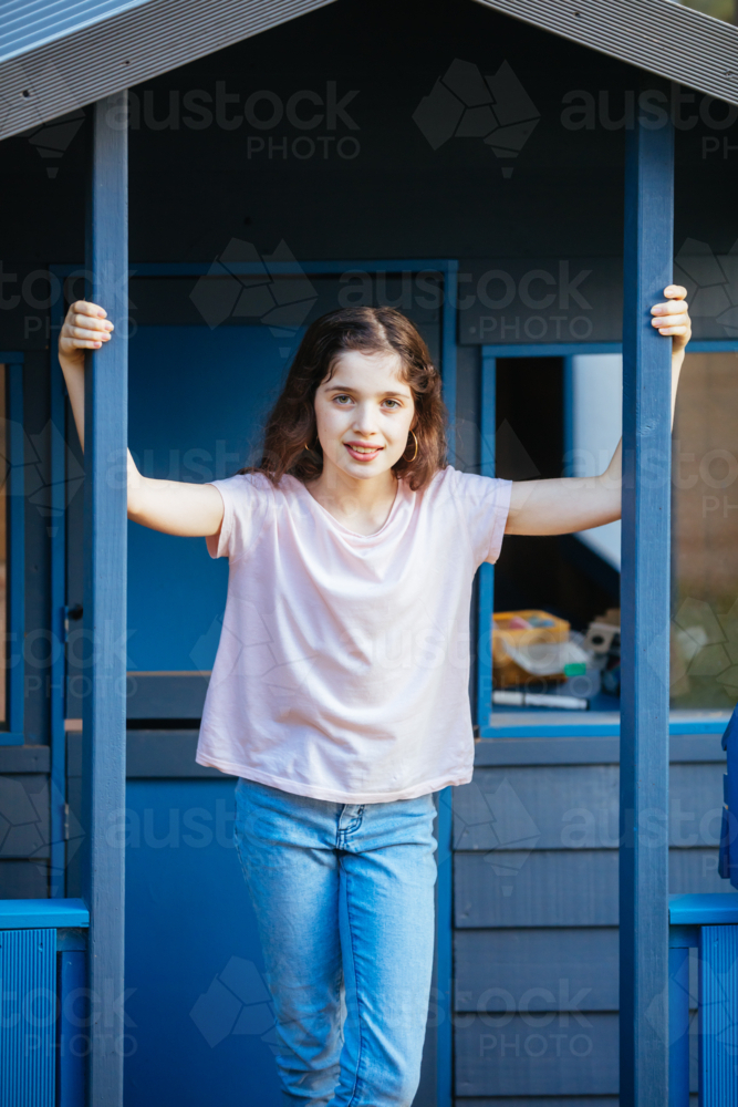A young caucasian girl poses in front of a cubby house on a sunny evening in Australia - Australian Stock Image