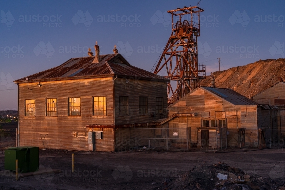 Abandoned sheds and poppet head at a mining plant at twilight - Australian Stock Image