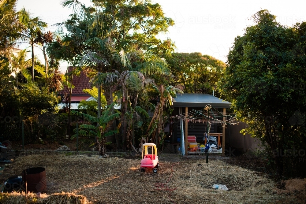 Abandoned toy car in green backyard - Australian Stock Image