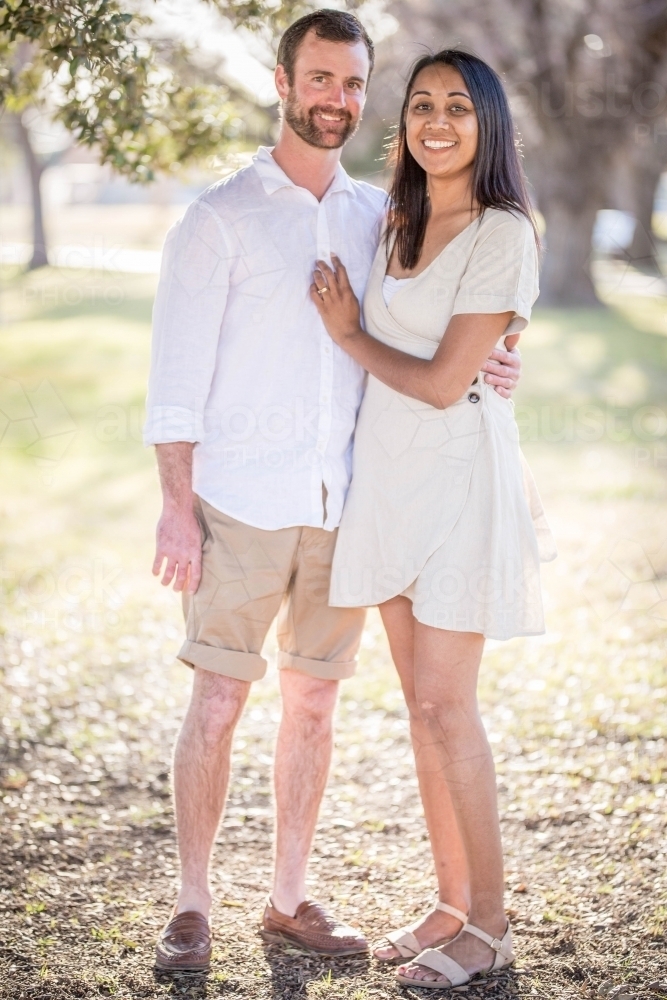 Aboriginal and caucasian husband and wife standing together smiling - Australian Stock Image