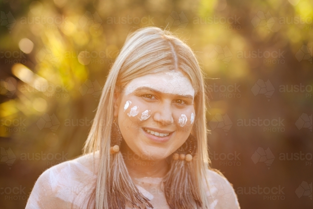 Aboriginal Australian woman in traditional ochre body paint at sunset - Australian Stock Image