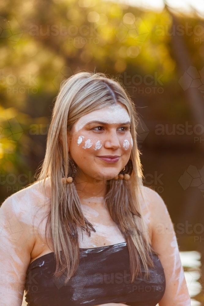 Aboriginal Australian woman in traditional ochre body paint at sunset - Australian Stock Image