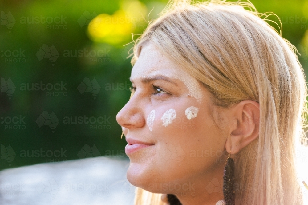 Aboriginal Australian woman on country in traditional dreamtime ochre body paint looking away - Australian Stock Image