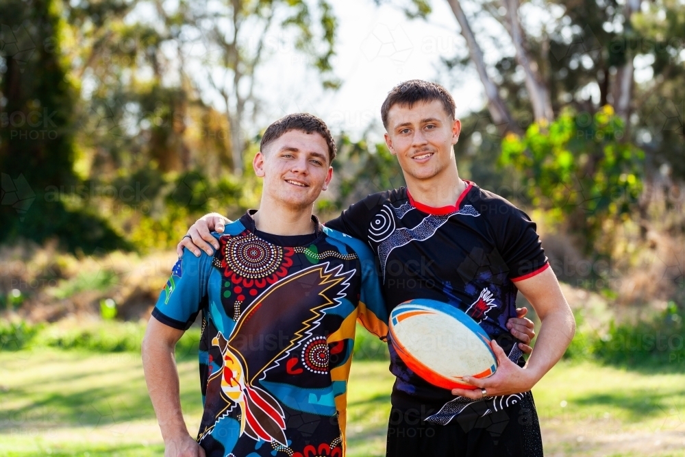 Aboriginal cousins on the edge of sports ground holding football - Australian Stock Image