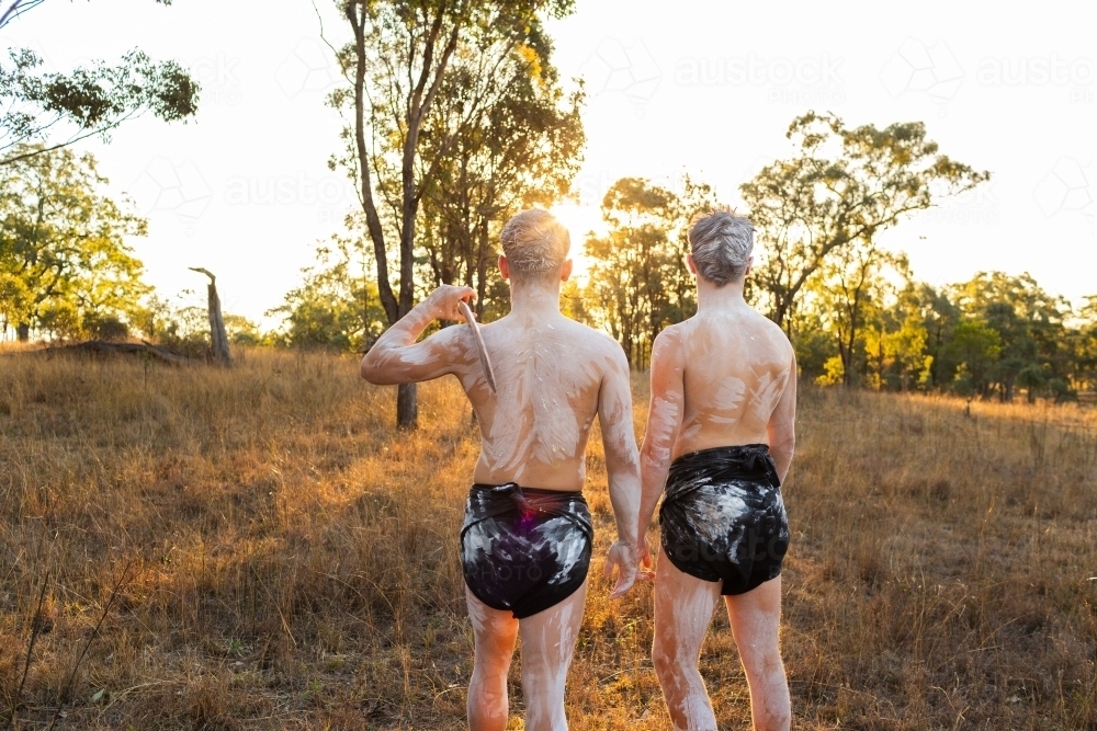 Aboriginal cousins standing together looking towards sunset - Australian Stock Image