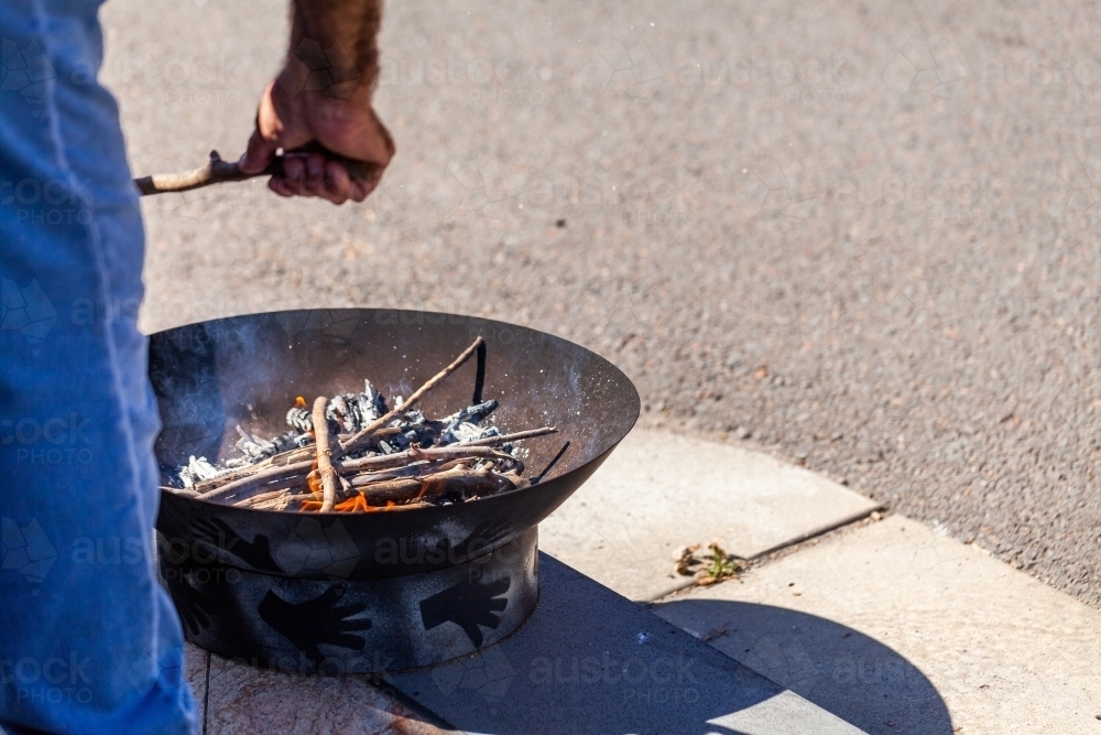 Aboriginal elder putting sticks in fire pit for smoking ceremony during freedom of entry parade - Australian Stock Image