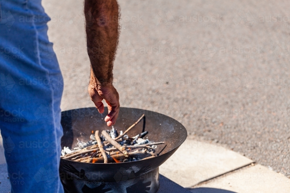 Aboriginal elder putting sticks in fire pit for smoking ceremony during freedom of entry parade - Australian Stock Image