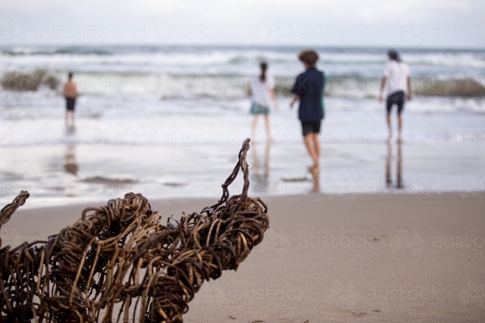 Aboriginal family playing in the ocean behind a traditional fish trap - Australian Stock Image