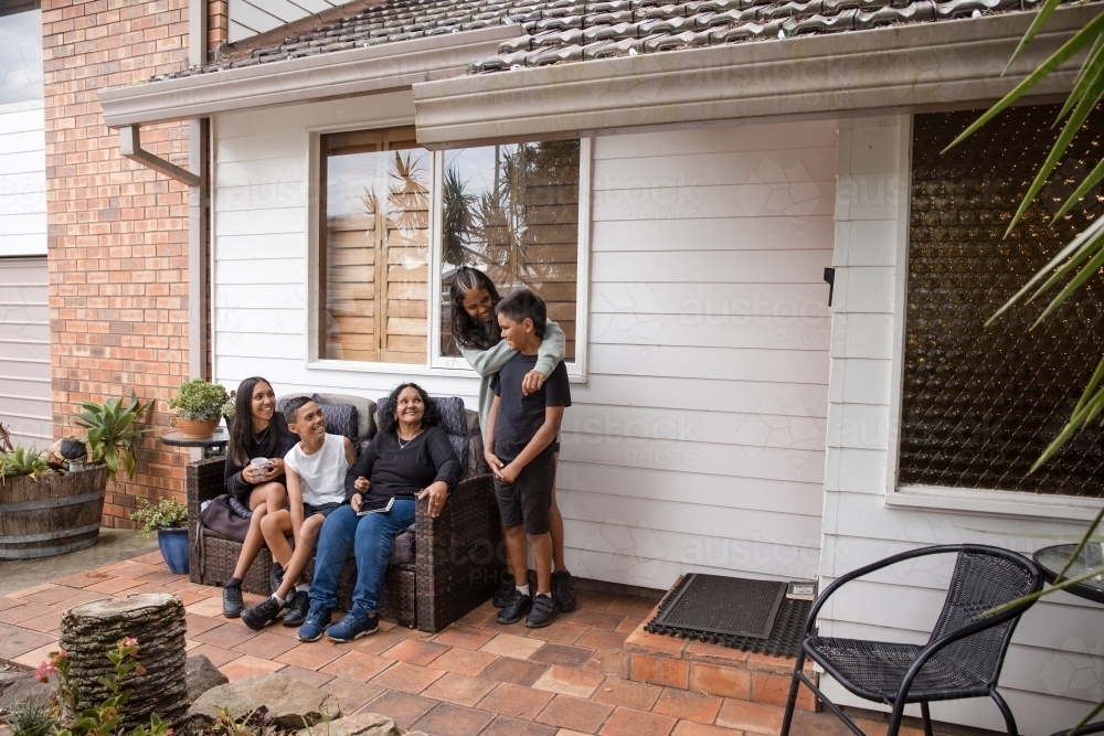 Aboriginal family sitting on back porch chair - Australian Stock Image