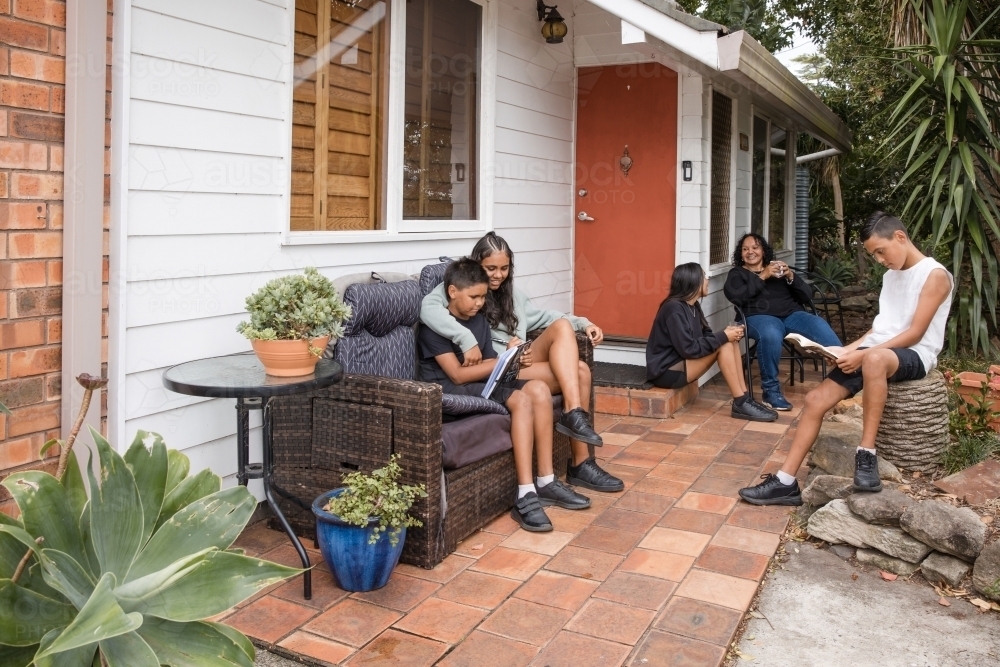 Aboriginal family sitting together on back porch - Australian Stock Image