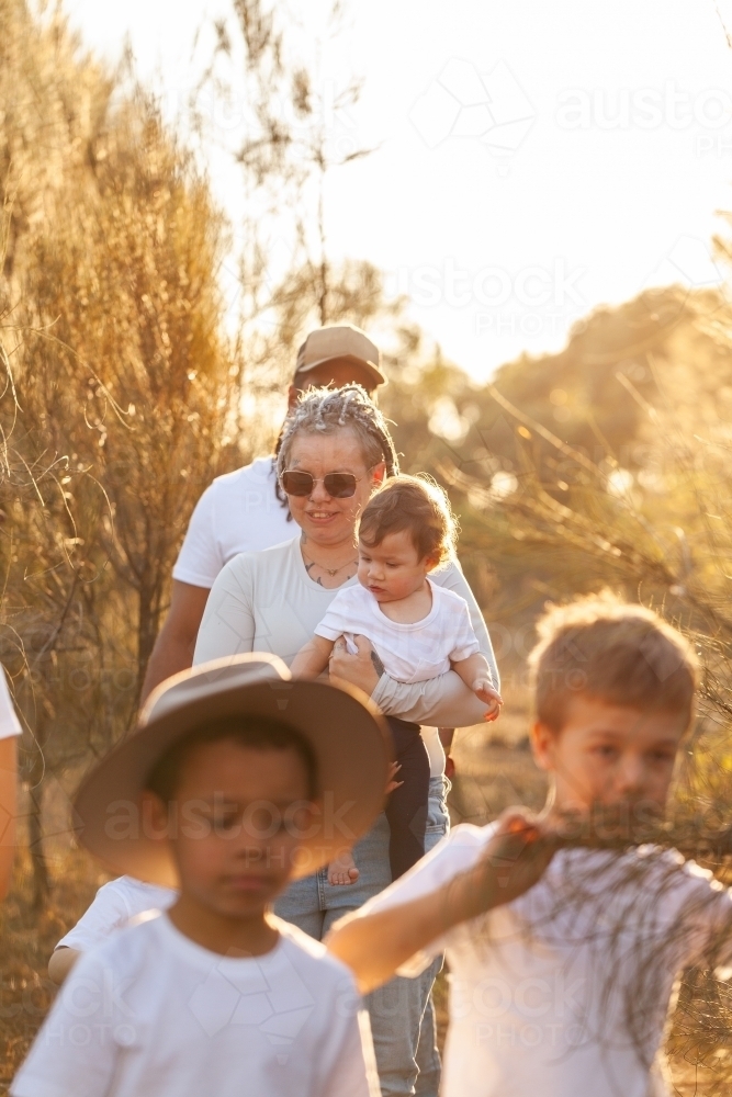 Aboriginal family walking together through bushland - Australian Stock Image