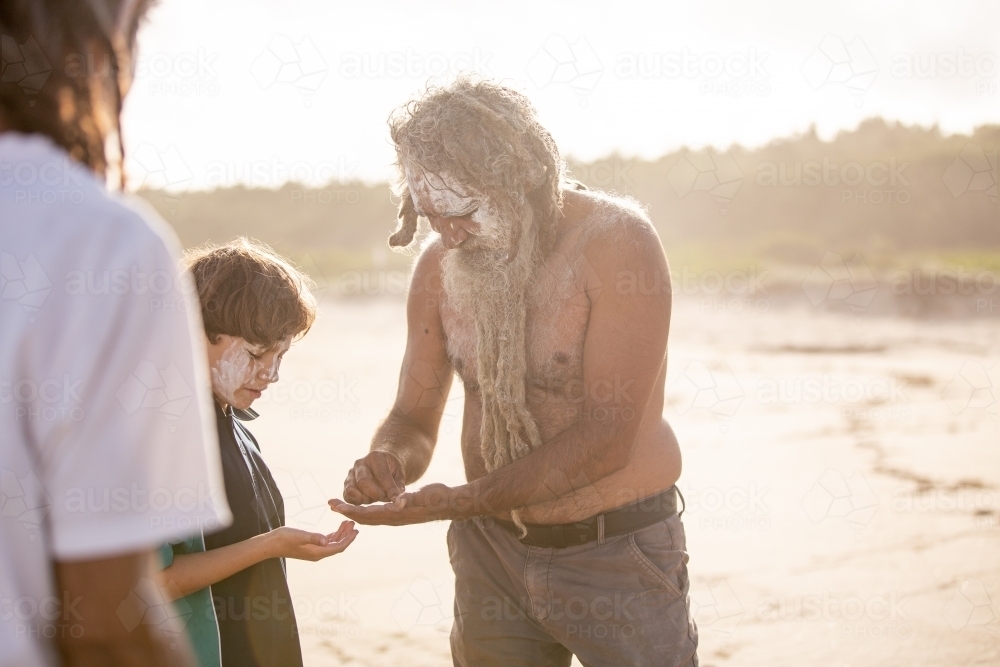 Aboriginal father helping son on a beach - Australian Stock Image