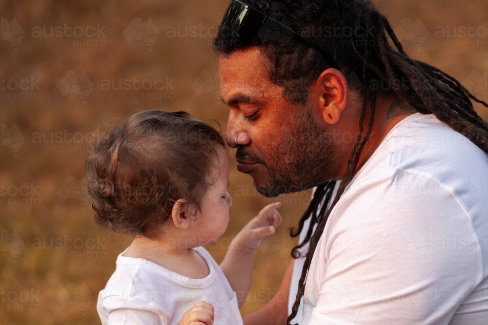 Image of Aboriginal father kissing baby girl - Austockphoto