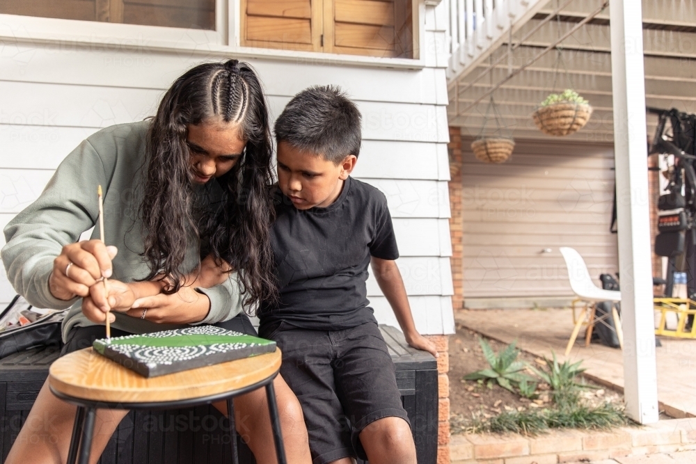 Aboriginal girl and boy dot painting together - Australian Stock Image