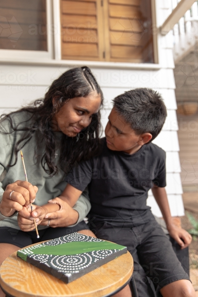 Aboriginal girl and boy dot painting together - Australian Stock Image