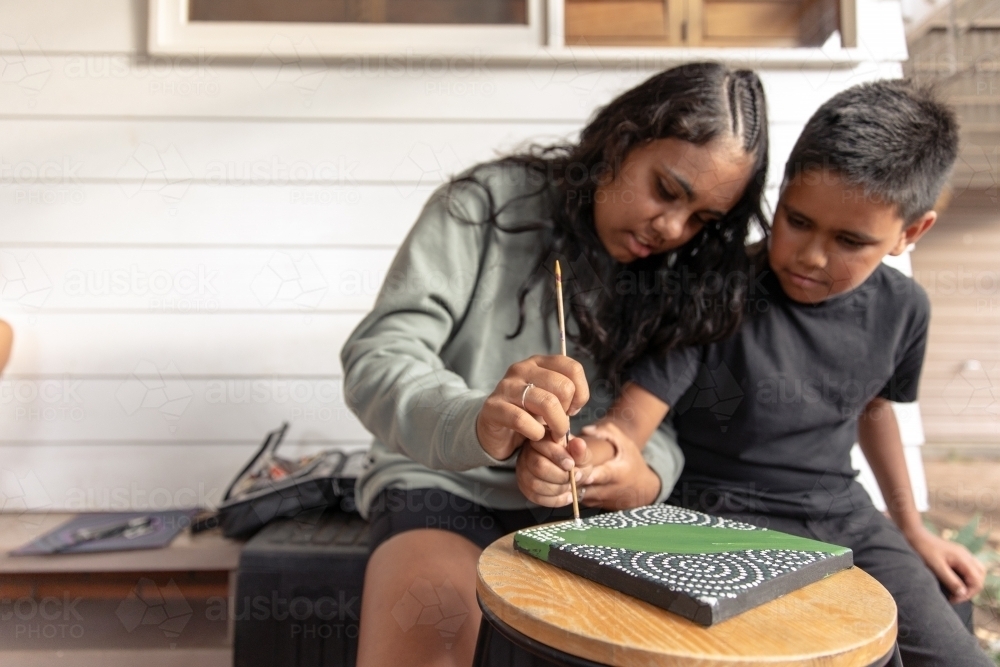 Aboriginal girl and boy dot painting together - Australian Stock Image