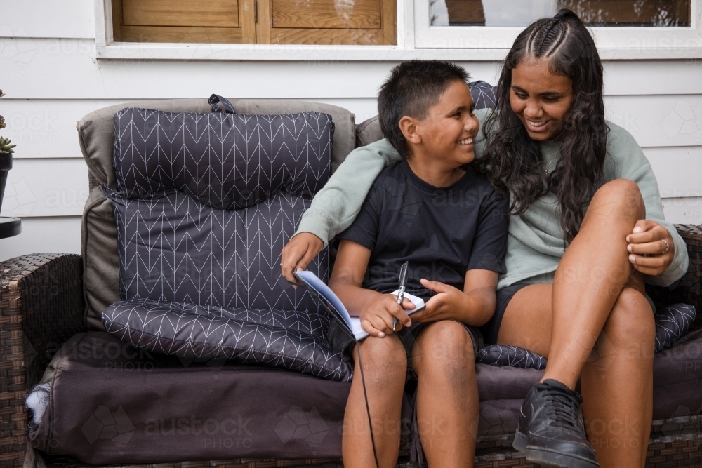 Aboriginal girl and young Aboriginal boy sitting together - Australian Stock Image