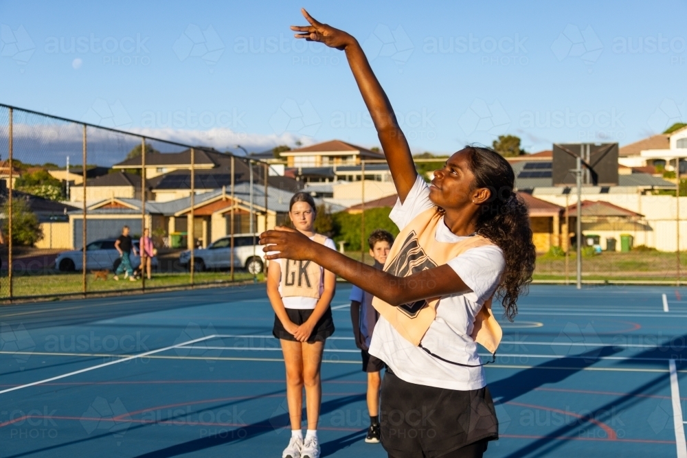 aboriginal girl shooting goal in netball team - Australian Stock Image