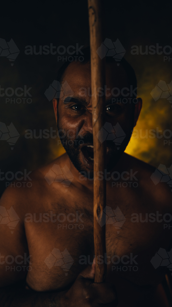 Aboriginal Male portrait yelling with spear - Australian Stock Image