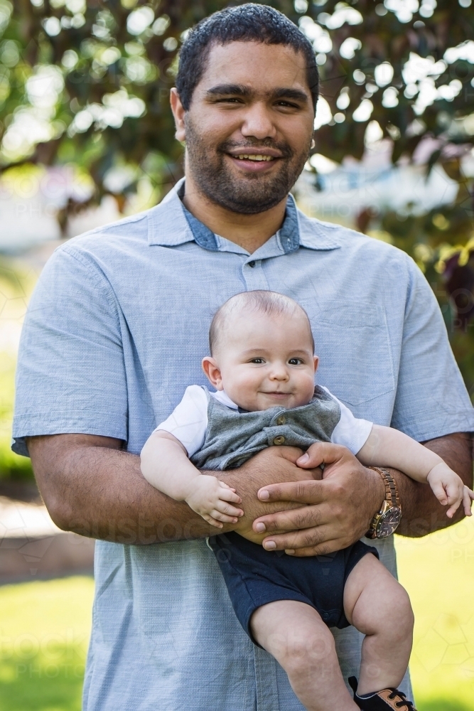 Aboriginal man holding baby smiling - Australian Stock Image