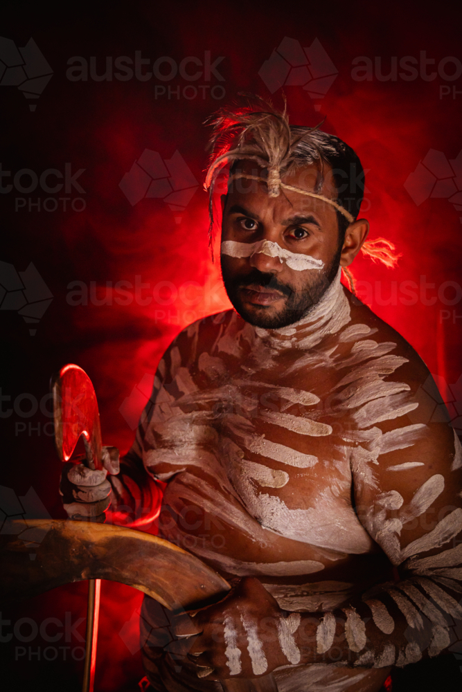 Aboriginal man holding boomerangs with red background - Australian Stock Image