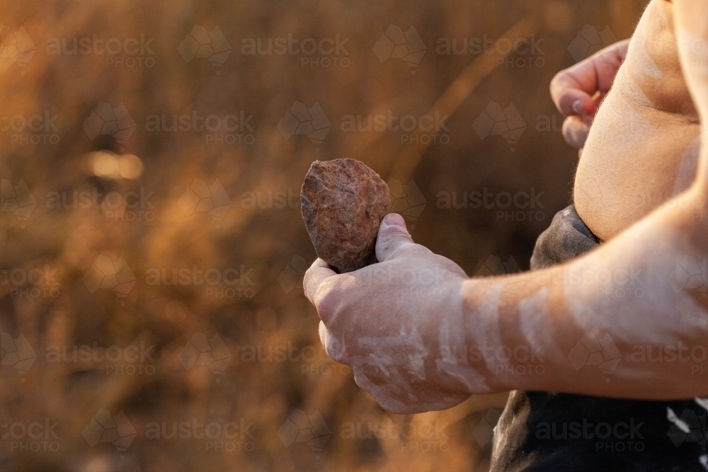 Aboriginal man holding stone artefact from axe head in hand - Australian Stock Image