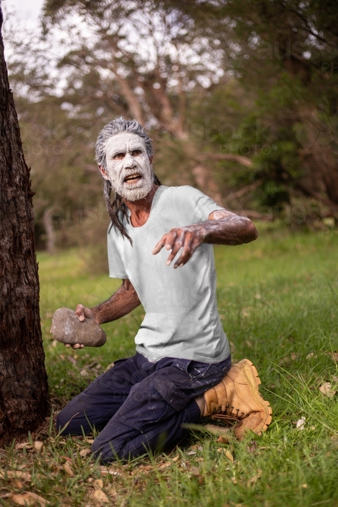 Aboriginal man in green bush surrounds telling stories - Australian Stock Image