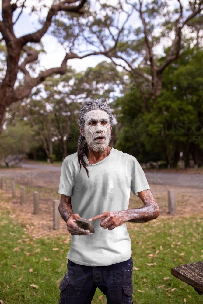 Aboriginal man in green bush surrounds telling stories - Australian Stock Image