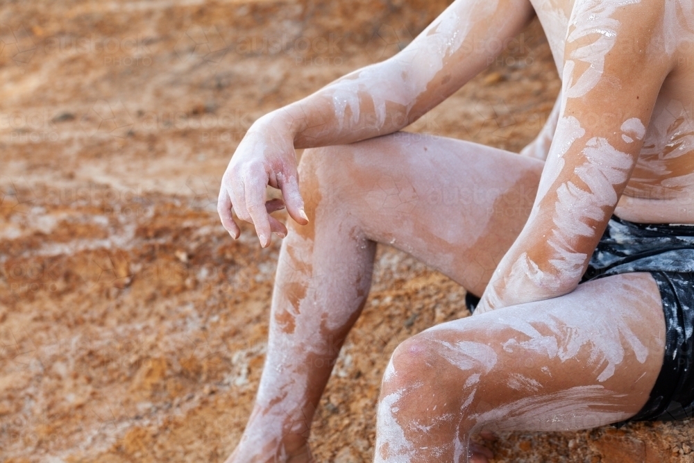 Aboriginal man in ochre body paint sitting on dry earth on country - Australian Stock Image