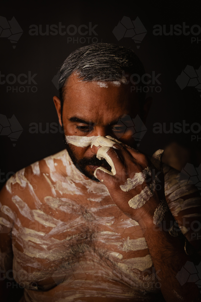 Aboriginal man painting his face with an ochre - Australian Stock Image